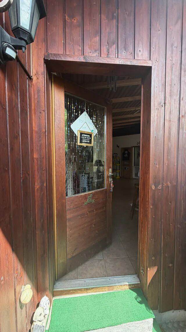 La porte d'entrée ouverte, rideau de perles et pancarte manuscrite sur la vitre.